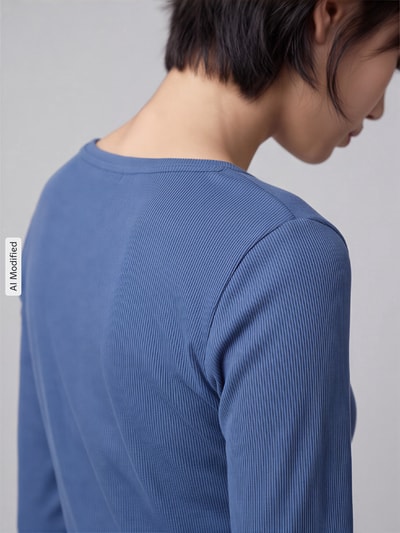 Frauenmodel trägt Slim Fit Langarmshirt aus Baumwoll-Lyocell-Mix von s.Oliver RED LABEL in gerippter blauer Struktur, Nahaufnahme Rückansicht, KI-modifiziertes Bild.