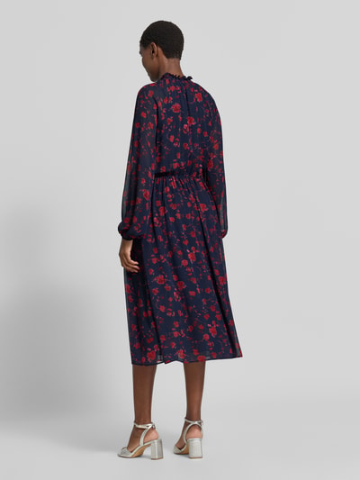 Frauenmodel trägt Midikleid mit Rüschenkragen und Raglanärmeln von Christian Berg Woman Selection, dunkelblau mit rotem Print, taillierter Schnitt, semitransparente Ärmel, blickdichtes Unterkleid, Ganzkörperansicht Rückansicht.