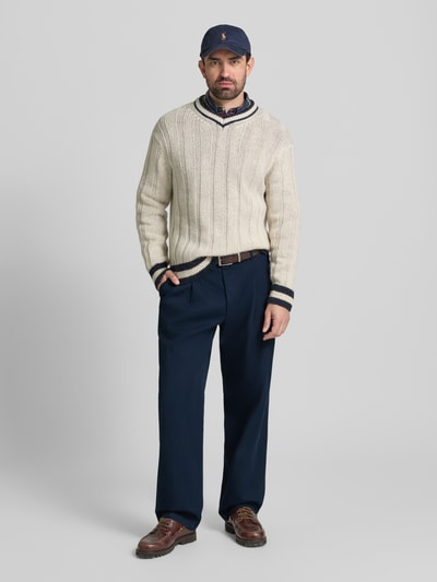 Mannenmodel draagt Wide Fit Bundfaltenhose aus reiner Baumwolle van Tommy Hilfiger, uni blauwe kleur, mid waist, 5-pocket, detailopname volledige vooraanzicht.