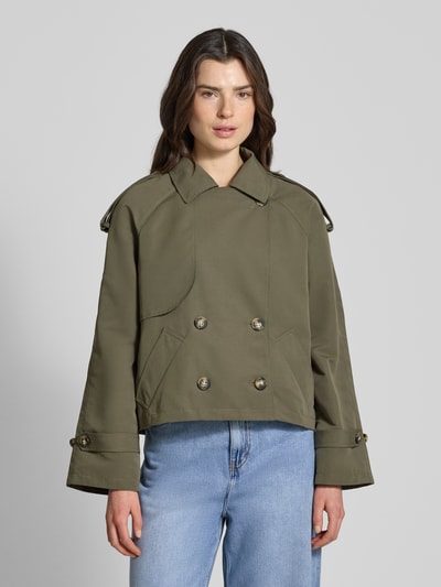Frauenmodel trägt Boxy Fit Trenchcoat mit doppelreihiger Knopfleiste Modell 'CHLOE' von Vero Moda in Khaki mit Umlegekragen, Ganzkörperansicht von vorne.