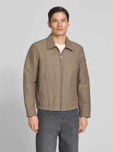 Männermodel trägt Regular Fit blouson met elastische rompzoom van Marc O'Polo in look: effen, met platte kraag, ritssluiting, labelpatch, lange mouw met drukknoop, zij-steekzakken en binnenzak, ganzkörperansicht von vorne.