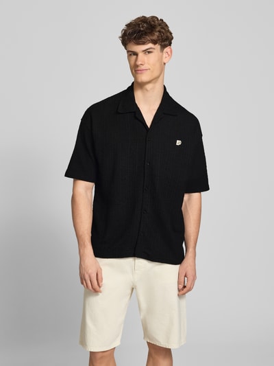 Männermodel trägt Regular Fit Freizeithemd mit Label-Patch Modell 'LIBCO' von Pegador im Material-Mix mit Baumwoll-Anteil, Schwarz, Reverskragen und Knopfleiste, Kurzärmeliges Design, Rückenlänge 72 cm, Schulterbreite 41 cm, Ärmellänge 35 cm; Ganzkörperansicht von vorne.