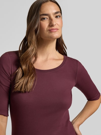 Frauenmodel trägt Damen T-Shirt mit Rundhalsausschnitt und Label-Detail von Marc Cain aus Baumwoll-Elasthan-Mix, Slim-Fit, Nahaufnahme Oberkörper.