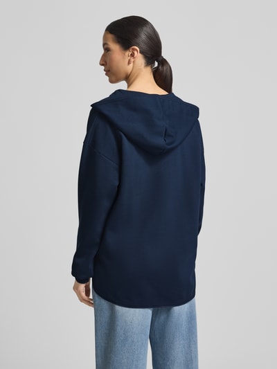 Frauenmodel trägt Oversized Hoodie aus Baumwoll-Mix Modell 'Tristani' von JOOP! in Dunkelblau mit Kapuze, verlängerte Rückseite, Ganzkörperansicht Rückansicht.