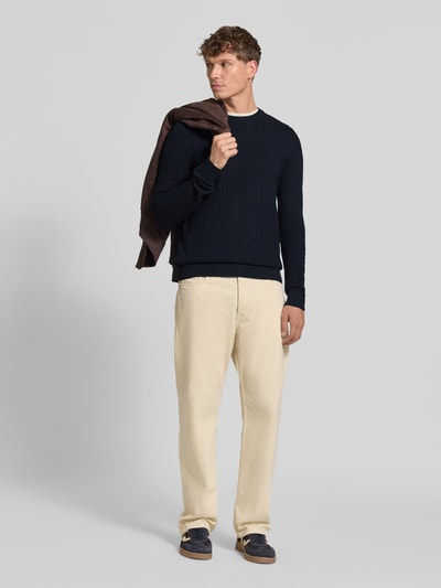 Männermodel trägt Regular Fit Pullover aus reiner Baumwolle Modell 'Adrian' von Strellson, dunkelblau, strukturierte Optik, helle Hose, Ganzkörperansicht von vorne, Herren Pullover von Strellson.