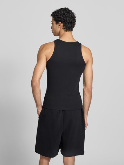Männermodel trägt Tanktop mit Label-Stitching van KARL KANI in zwart katoenmix met structuurpatroon en ronde hals, slim fit. Ganzkörperansicht Rückansicht.