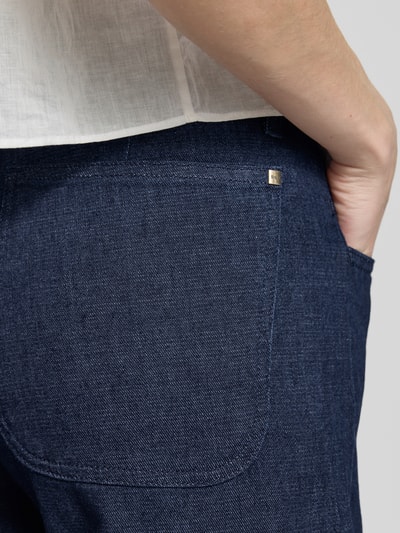 Frauenmodel trägt Wide Leg Jeans aus Baumwoll-Mix Modell 'STYLE.MAINE' von Brax, dunkler Denim, sichtbare Metall-Applikation, Nahaufnahme Rückansicht.