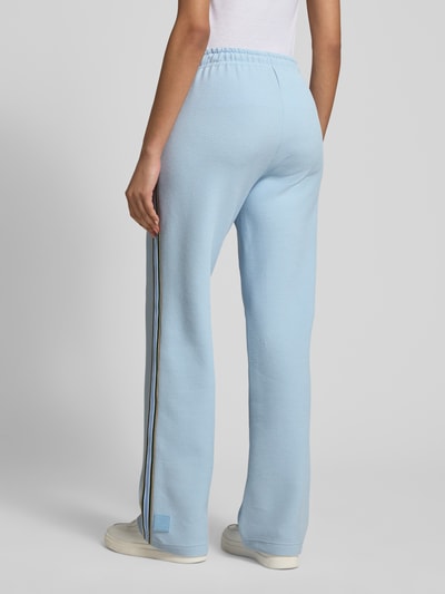 Männermodel trägt Wide Fit Sweatpants mit Strukturmuster von Marc Cain, mieszanka bawełny, krój wide fit, tunel, fakturowany wzór, długość wewnętrzna nogawki 89 cm, szerokość w rozmiarze 36: 39 cm, jasnoniebieski kolor, widok całej sylwetki z tyłu.