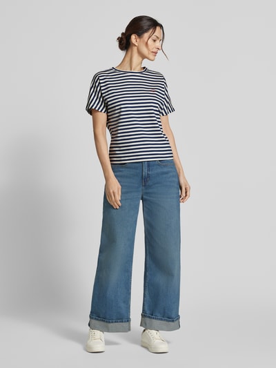 Modelka nosi damski t-shirt z bawełny o kroju regular fit, wzór w paski, haft, okrągły dekolt, model 'Salentine stripe' od OPUS, długość tyłu w rozmiarze 36: 56 cm, widok całej sylwetki z przodu.