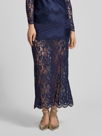 Frauenmodel trägt Maxirock mit Spitzenbesatz von Rabanne in Dunkelblau, semitransparentes Satin-Design, schmale Passform, Nahaufnahme Unterkörper.