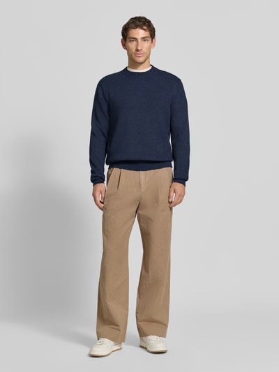 Männermodel trägt Regular Fit Pullover aus Viskose-Mix Modell 'MATTI' von Jake*s Studio Men in Dunkelblau, beige Hose, weiße Schuhe, Ganzkörperansicht von vorne.
