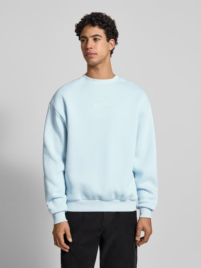 Männermodel trägt Sweatshirt mit Label-Stitching von KARL KANI, hellblau, Baumwoll-Mix, lockerer Schnitt, gerippte Abschlüsse, Rundhalsausschnitt, Rückenlänge 69 cm, Ärmellänge 65 cm, Ganzkörperansicht von vorne.