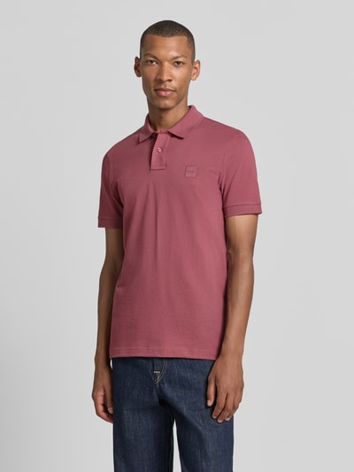 Männermodel trägt Regular Fit Poloshirt aus Baumwoll-Mix Modell 'Passenger' von BOSS Orange in Altrosa, klassische Knopfleiste, Ganzkörperansicht von vorne. Herren Poloshirt von BOSS Orange.