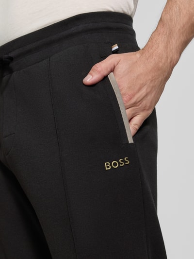 Männermodel trägt Regular Fit Sweatpants aus Baumwoll-Mix Modell 'Sense Pants' von BOSS in Schwarz, Nahaufnahme Oberkörper, Herren Sweatpants von BOSS.