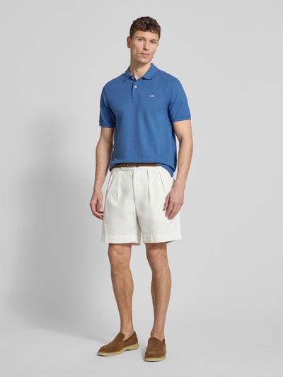 Männermodel trägt Slim Fit Poloshirt mit Logo-Stitching van Gant, puur katoen, slim fit, polokraag, korte mouw, ruglengte maat M 70 cm, ganzkörperansicht von vorne.
