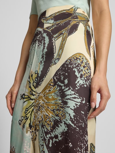 Frauenmodel trägt Midirock aus Viskose im Allover-Look von Marc Cain mit floralen Mustern, Reißverschluss und Gehschlitz, Nahaufnahme Oberkörper.