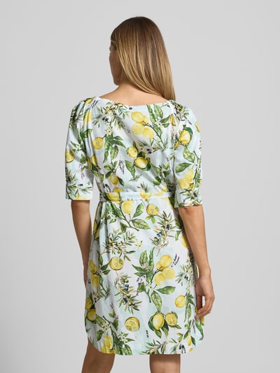 Frauenmodel trägt Minikleid mit Bindegürtel von Marc Cain in Weiß mit gelbem und grünem Allover-Look, Baumwolle, Rückansicht, Ganzkörperansicht.