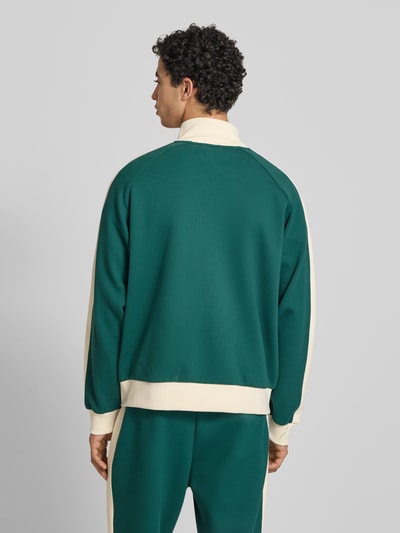 Männermodel trägt Regular Fit Sweatjacke mit Stehkragen von KARL KANI, grün mit cremefarbenen Details, Rückenansicht, Elastischer-Material-Mix, Reißverschluss, Logo-Stitching, Eingrifftaschen, elastische Abschlüsse, Herren, Rückenlänge 60 cm, Ärmellänge 48 cm. Ganzkörperansicht Rückansicht.