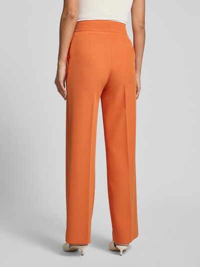 Frauenmodel trägt Wide Leg Weite Hose mit Gürtelschlaufen Modell 'HIMIA-1' von HUGO in Orange, glatte Textur, Damen Weite Hose, Ganzkörperansicht Rückansicht.