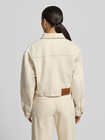 Frauenmodel trägt Regular Fit Jeansjacke aus reiner Baumwolle Modell 'GISOLIA' von HUGO in heller Denim-Optik mit Umlegekragen, Rückansicht.