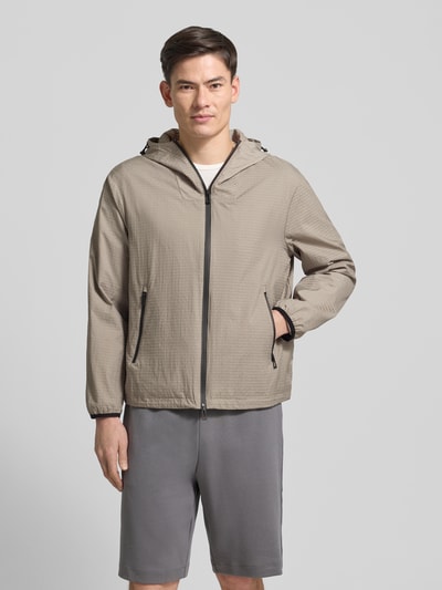 Männermodel trägt Jacke mit Zweiwege-Reißverschluss von Emporio Armani, Regular-Fit, Kapuze mit Tunnelzug, Reißverschlusstaschen, beige, Ganzkörperansicht von vorne. Rückenlänge 67 cm, Schulterbreite 54 cm, Brustweite 60 cm, Ärmellänge 63 cm, Größe 50.