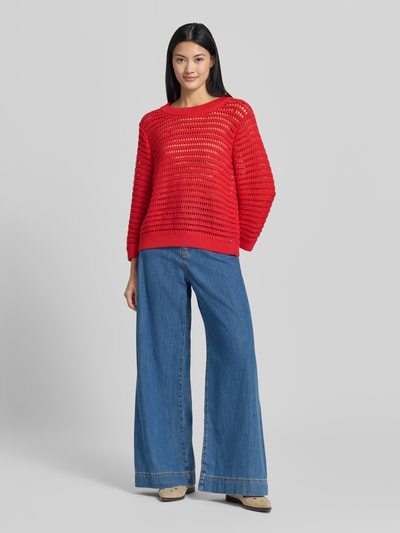 Vrouwenmodel draagt Oversized Pullover in semitransparentem Design Model 'Ajour' van monari, puur katoen, oversized fit, tricotlook, ruglengte maat 36: 54 cm, mouwlengte maat 36: 49 cm, felrood met open ajourpatroon, rechte vormen, grof gebreide textuur. Ganzkörperansicht van voren.