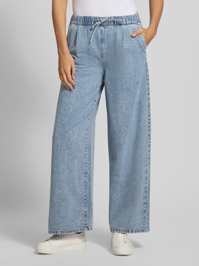 Frauenmodel trägt Wide Leg Jeans aus Baumwoll-Viskose-Mix Modell 'VALERIA' von Vero Moda, hellblau, elastischer Bund, seitliche Eingrifftaschen, Denim-Optik, Ganzkörperansicht von vorne.