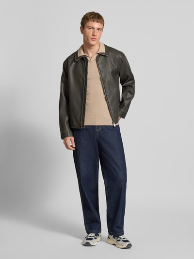 Männermodel trägt Slim Fit Poloshirt in Strick-Optik Modell 'Kane' von JACK & JONES aus reiner Baumwolle, Kurzärmelig, Polokragen, Ganzkörperansicht von vorne.