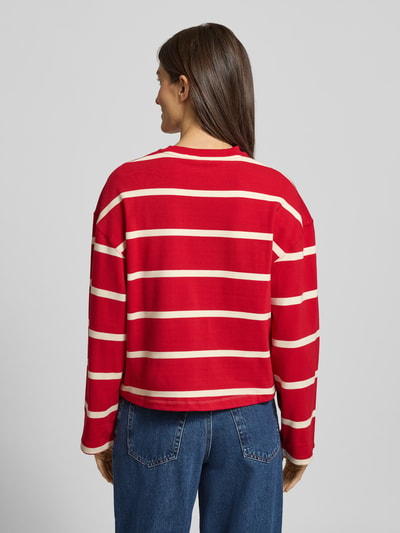 Frauenmodel trägt Relaxed Fit Sweatshirt aus Baumwoll-Mix von Tommy Hilfiger mit rot-beigem Streifenmuster und Logo-Stitching, Ganzkörperansicht Rückansicht.