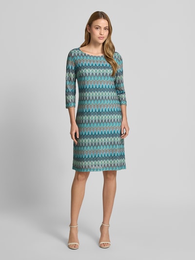 Frauenmodel trägt Regular Fit Kleid in Strick-Optik von Betty Barclay in Türkis mit Zickzack-Muster, knielang, U-Boot-Ausschnitt, 3/4-Arm, Ganzkörperansicht von vorne. Rückenlänge bei Größe 36: 98 cm, Brustweite: 46 cm, Ärmellänge: 45 cm.