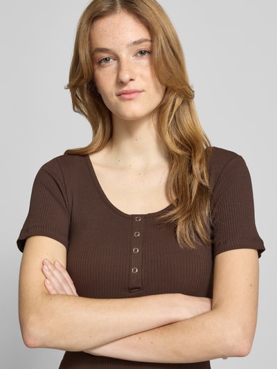 Frauenmodel trägt braunes Damen T-Shirt Slim Fit T-Shirt aus Baumwoll-Mix Modell 'KITTE' von Pieces, fein gerippte Textur, Nahaufnahme Oberkörper. Damen T-Shirt von Pieces.