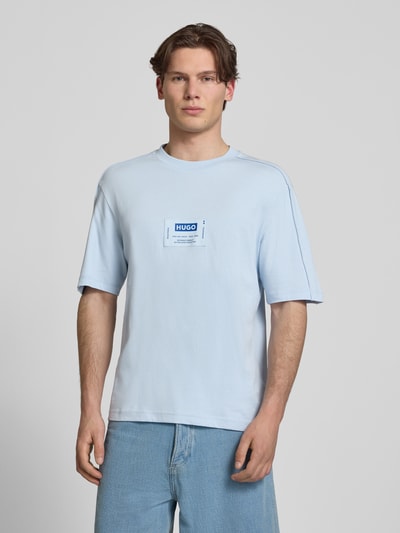 Männermodel trägt Regular Fit T-Shirt aus reiner Baumwolle Modell 'NURAZTI' von Hugo Blue, hellblau, unifarben, Label Patch, Ganzkörperansicht von vorne