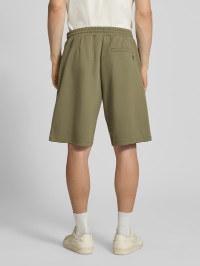 Männermodel trägt Shorts mit elastischem Bund und Ziernähten von REVIEW in Khaki, Material-Mix mit Stretch-Anteil, Loose-Fit, Ganzkörperansicht Rückansicht.