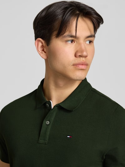 Männermodel trägt Regular Fit Poloshirt Modell 'TJM SLIM PLACKET POLO EXT' von Tommy Jeans, Optik: Unifarben, Logo-Stitching, Polokragen, 2-Knopf-Verschluss, Material: Reine Baumwolle, Nahaufnahme Oberkörper.