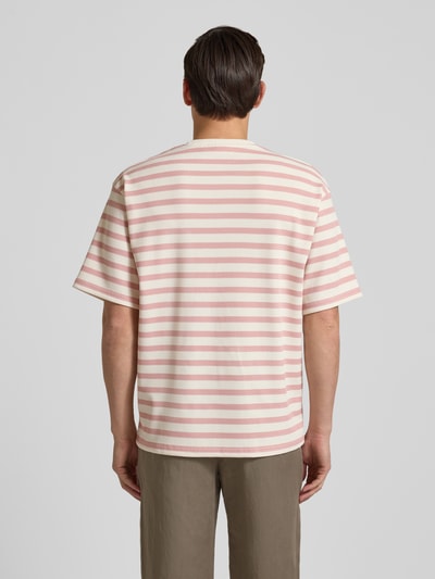 Männermodel trägt Oversized T-Shirt mit Rundhalsausschnitt Modell 'Gael' von Redefined Rebel, beige-rosafarbene Streifen, elastischer Material-Mix, Rückenlänge bei Größe M 75 cm, Ganzkörperansicht Rückansicht.