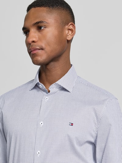 Männermodel trägt Slim Fit Freizeithemd aus Baumwoll-Mix von Tommy Hilfiger, kariertes Muster, Logo-Detail, Nahaufnahme Oberkörper.
