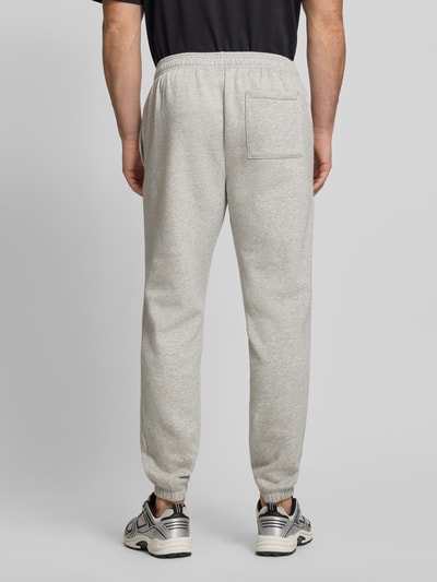 Männermodel trägt Sweatpants mit Logo und elastischem Bund von GAP in Hellgrau aus Baumwoll-Mix, Regular-Fit, Innenbeinlänge 78 cm, Ganzkörperansicht Rückansicht.