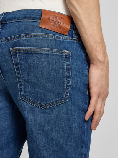 Männermodel trägt Slim Fit Jeans mit 5-Pocket-Design von Calvin Klein Jeans, Baumwoll-Mix mit Stretch-Anteil, Label-Detail, Detailaufnahme Rückansicht.