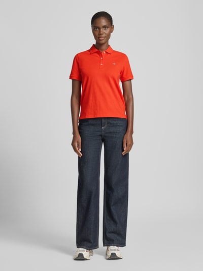 Frauenmodel trägt Poloshirt mit Logo-Stitching und Polokragen von Gant in Rot aus Reine Baumwolle, Regular-Fit, Ganzkörperansicht von vorne.