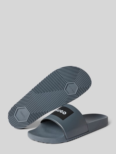 Produktfoto, Badeschuhe mit Logo-Print Modell 'TIMEIN_SLID_PH' von HUGO in Two-Tone-Optik mit runder Schuhspitze und flacher Absatzform.
