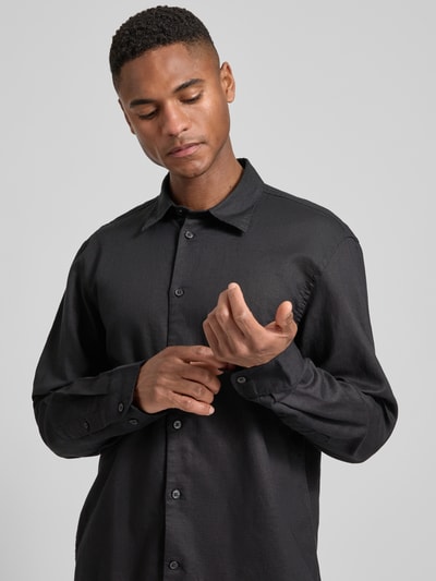Männermodel trägt Regular Fit Freizeithemd aus Leinen-Baumwoll-Mix Modell 'CLAY LINENBLEND' von SELECTED HOMME in schwarzer Melange-Optik, Kentkragen, durchgehende Knopfleiste, Rückenpasse, 2-Knopf-Manschette, Materialverarbeitung Flammgarn, Nahaufnahme Oberkörper.