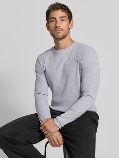 Męski model nosi bluzkę z długim rękawem Slim Fit Longsleeve aus reiner Baumwolle Modell 'Enil' od DRYKORN, szary kolor, fakturowany wzór, okrągły dekolt, krój slim fit, bawełna, Długość tyłu w rozmiarze M 67 cm, Długość rękawów w rozmiarze M 69 cm, zdjęcie całej sylwetki z przodu.