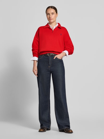 Kobiecy model nosi Regular Fit Pullover aus Baumwoll-Mix von Polo Ralph Lauren w kolorze czerwonym, połączony z ciemnymi dżinsami, Ganzkörperansicht von vorne.
