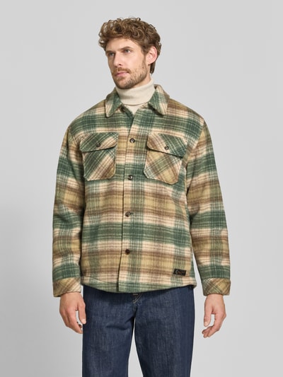 Männermodel trägt Regular Fit Hemdjacke mit Brusttaschen von Scotch & Soda, grünes und beigefarbenes Karo, Kentkragen, Knopfleiste, Ganzkörperansicht von vorne. Mix mit Woll-Anteil, Allover-Look, Rückenlänge bei Größe M: 72 cm.