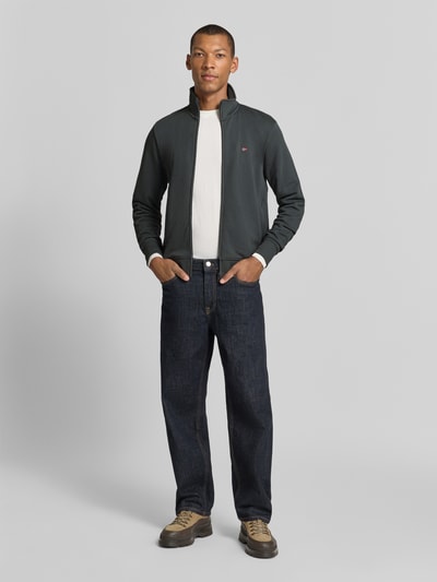 Mannelijk model draagt donkere sweatjack met opstaande kraag en labelstitching, puur katoen, slim fit, Model 'BALIS' van Napapijri, ritssluiting, ruglengte maat M 65 cm, mouwlengte maat M 69 cm, voorkant volledige lichaamsopname.