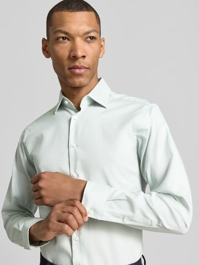 Männermodel trägt Regular Fit Business-Hemd mit Kentkragen von Christian Berg Men in Reine Baumwolle, Knopfleiste, Sportmanschetten, abgerundeter Saum, hellgrün, Nahaufnahme Oberkörper. Rückenlänge 78 cm, Schulterbreite 43 cm, Ärmellänge 65 cm bei Größe 39/40.