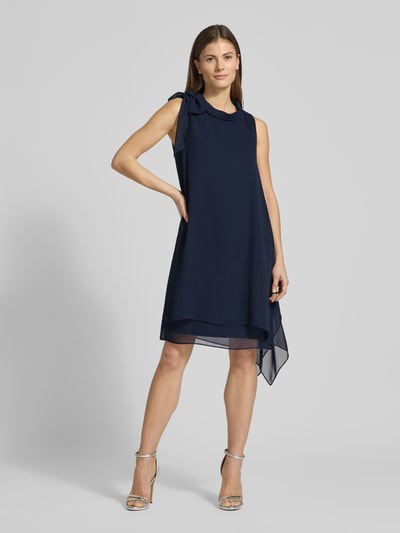 Modelka kobieca ma na sobie Relaxed Fit Sukienka z stójką od Vera Mont, półprzezroczysty materiał, ozdobna kokarda, halka pod sukienkę, krój bez rękawów, długość tyłu w rozmiarze 36: 98 cm, szerokość w rozmiarze 36: 29 cm, sukienka w kolorze granatowym, gładka tekstura, Ganzkörperansicht von vorne.