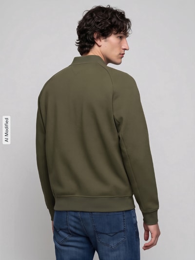 Männermodel trägt Regular Fit Sweatjacke aus Baumwoll-Mix von Tommy Hilfiger in Olivgrün mit glatter Struktur, Ganzkörperansicht Rückansicht, KI-modifiziertes Bild.
