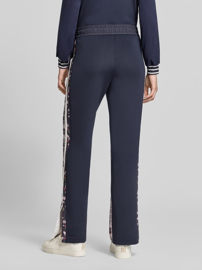 Frauenmodel trägt Straight Fit Hose mit floralem Print von Marc Cain, kwiatowy nadruk, tunel, elastyczny pas, szerokość w rozmiarze 36: 36 cm, długość wewnętrzna nogawki w rozmiarze 36: 68 cm, widok całej sylwetki z tyłu