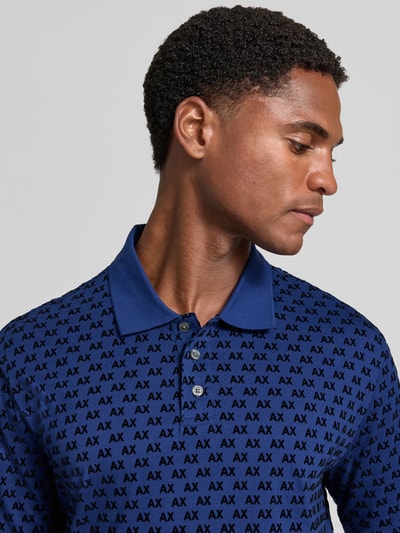 Männermodel trägt Regular Fit Poloshirt aus reiner Baumwolle von Armani Exchange in Blau mit Allover-Logo-Print, Nahaufnahme Oberkörper.